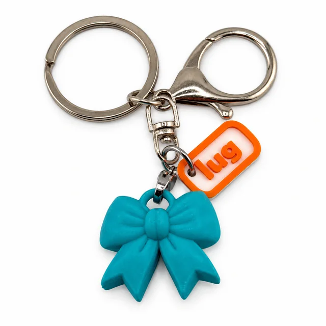 An aquamarine bow key chain with a silver ring, clasp, and orange Lug charm.