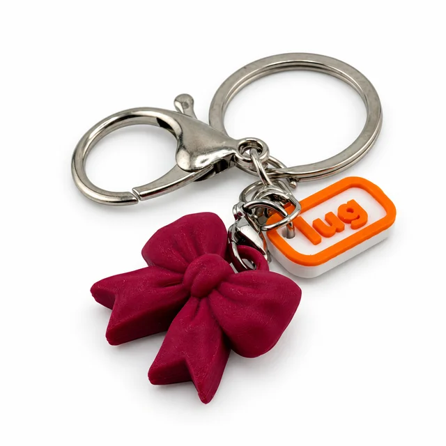 A wine-colored bow key chain with a silver ring, clasp, and orange Lug charm.