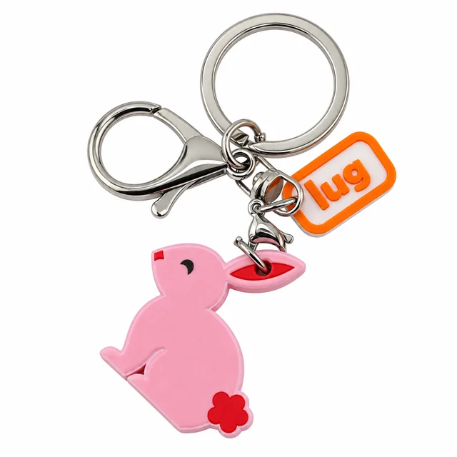 A pink rabbit key chain with a red flower, silver ring, and orange Lug charm.
