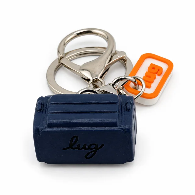 A navy blue miniature Lug trolley bag key chain with a silver ring and orange Lug charm.